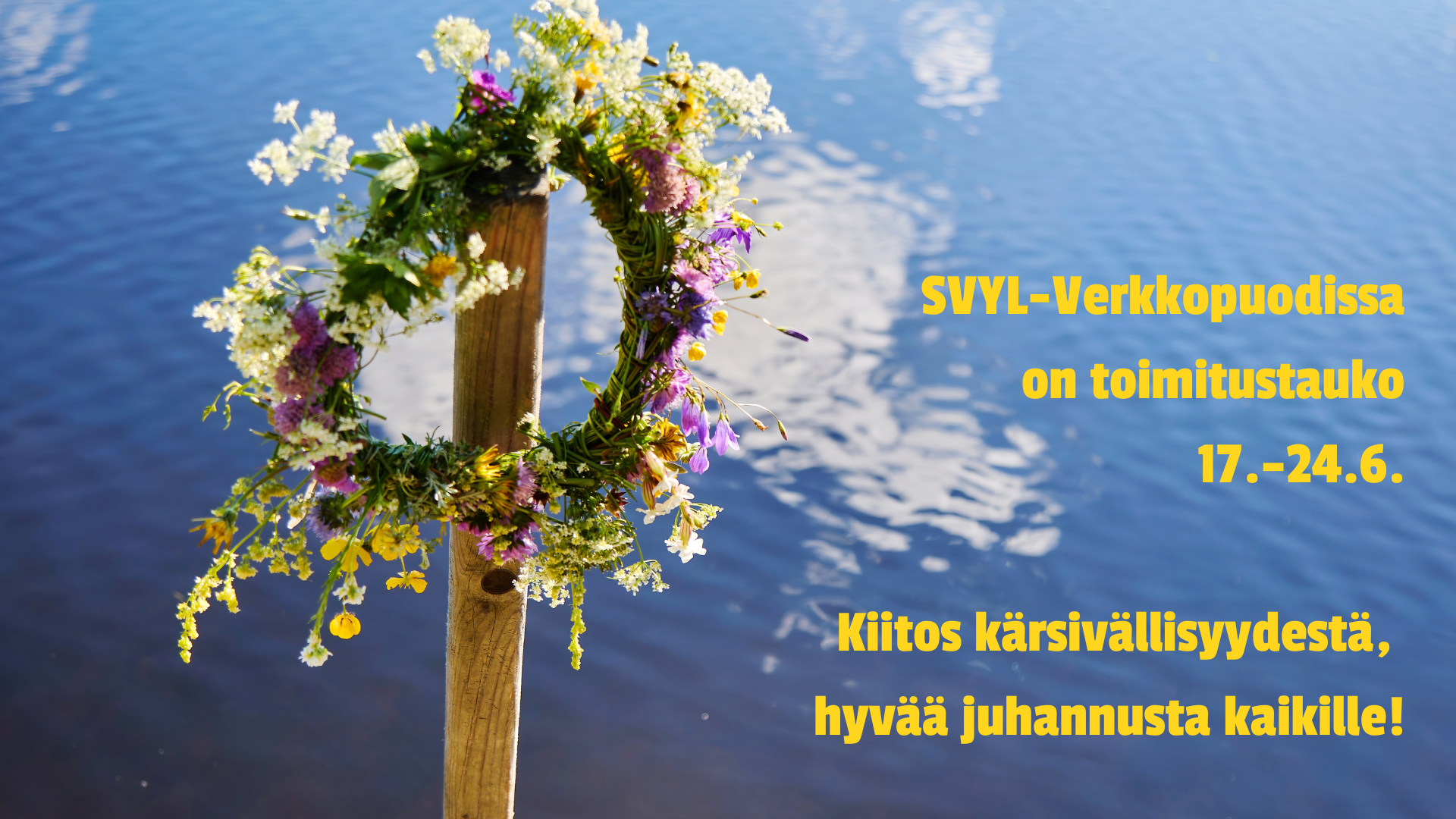 Kuvassa on kukkaseppele seipään päässä veden äärellä.